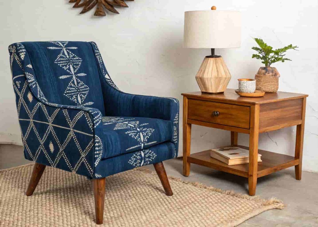Accent armchair reupholstered in deep indigo Adire fabric beside a wooden side table in a minimal Afrobohemian room