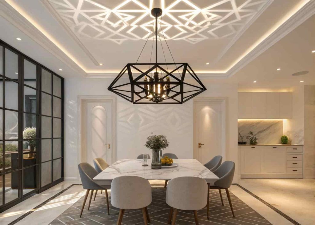 An angular matte black geometric chandelier above a marble dining table in a modern dining room, casting decorative shadow patterns on the ceiling.