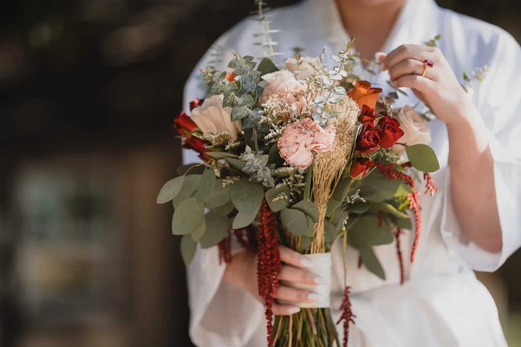 Bride holding a minimal white rose bouquet tied with silk ribbon on her wedding day