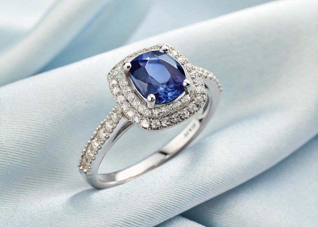 A striking blue sapphire engagement ring with diamond halo accent on a white gold band