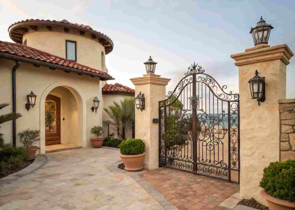 Mediterranean villa exterior entry gate with wrought iron, stucco wall, and stone pillars