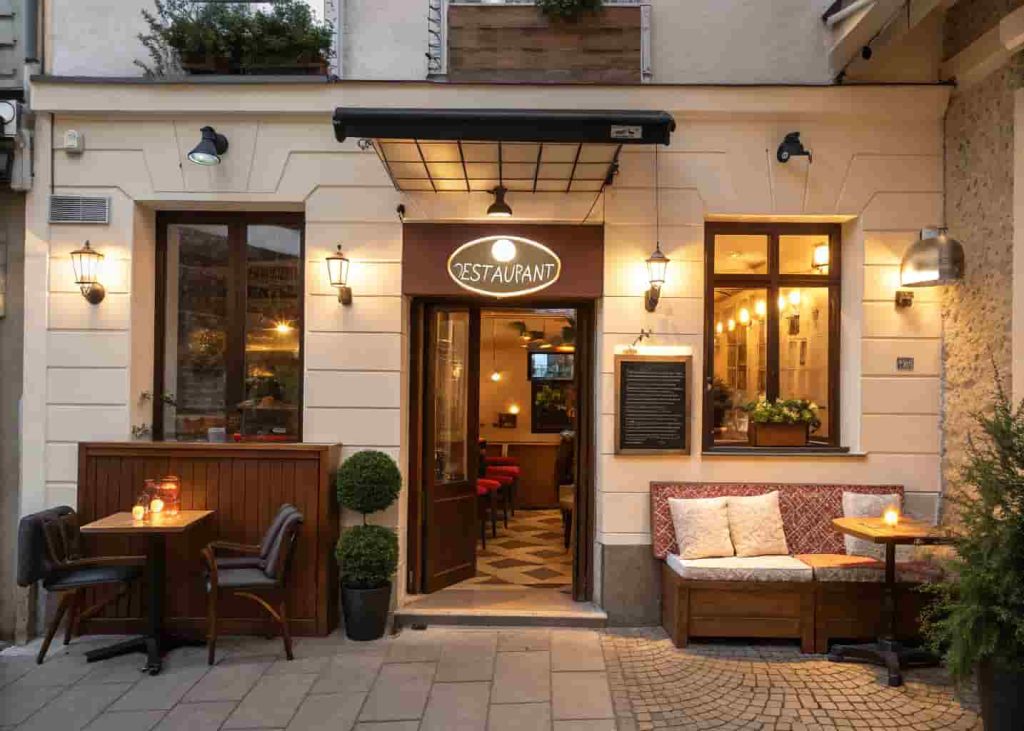 Inviting restaurant entrance with warm lighting, branded signage, and a small waiting area with comfortable seating