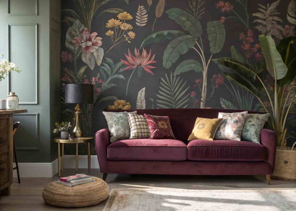 A bold botanical patterned statement wallpaper wall in a maximalist living room with a velvet sofa and coordinating colorful accessories.