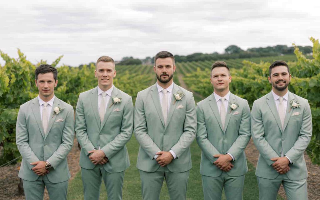 Matching sage green groomsmen attire at a vineyard wedding