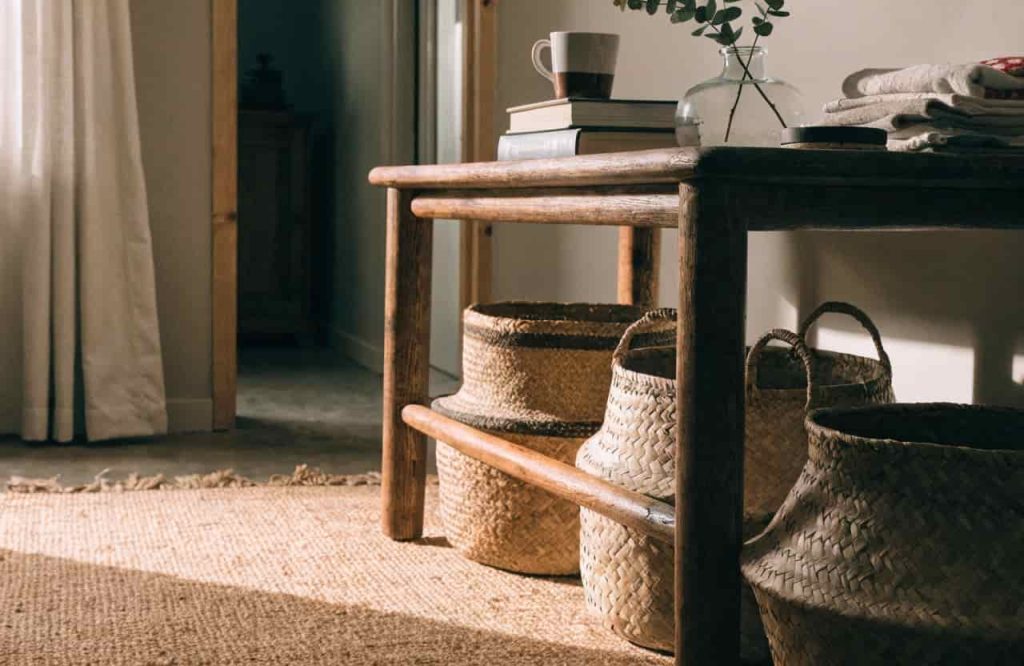 Woven baskets placed under a console table on a jute rug
