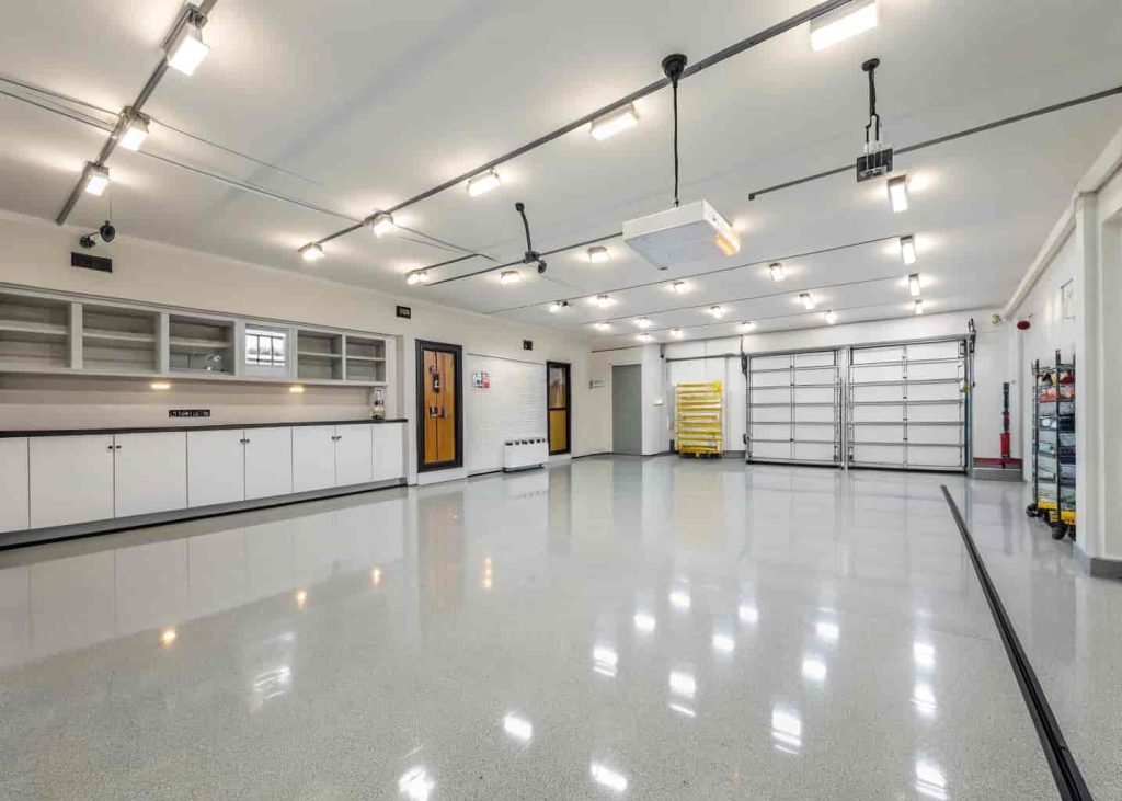 Well-lit garage interior with hanging LED shop lights casting bright white light across organized shelves and clean floor