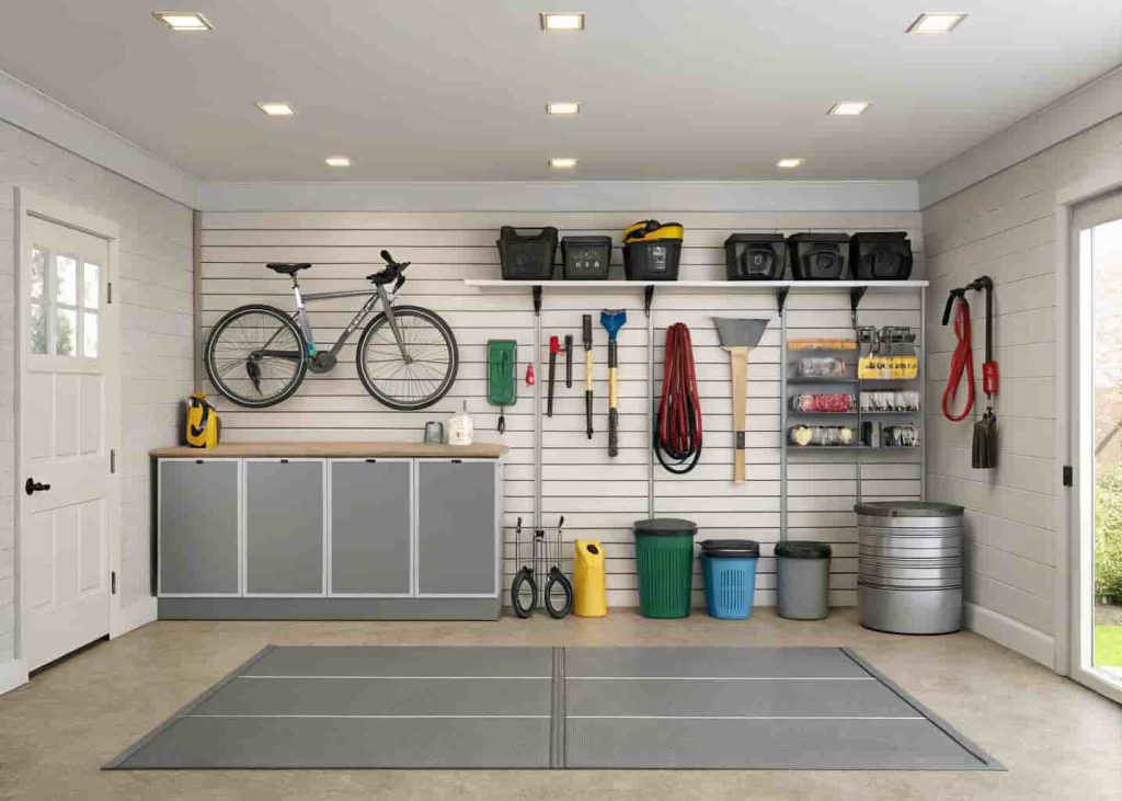 Garage wall with slatwall storage system holding bikes, garden tools, and labeled storage bins