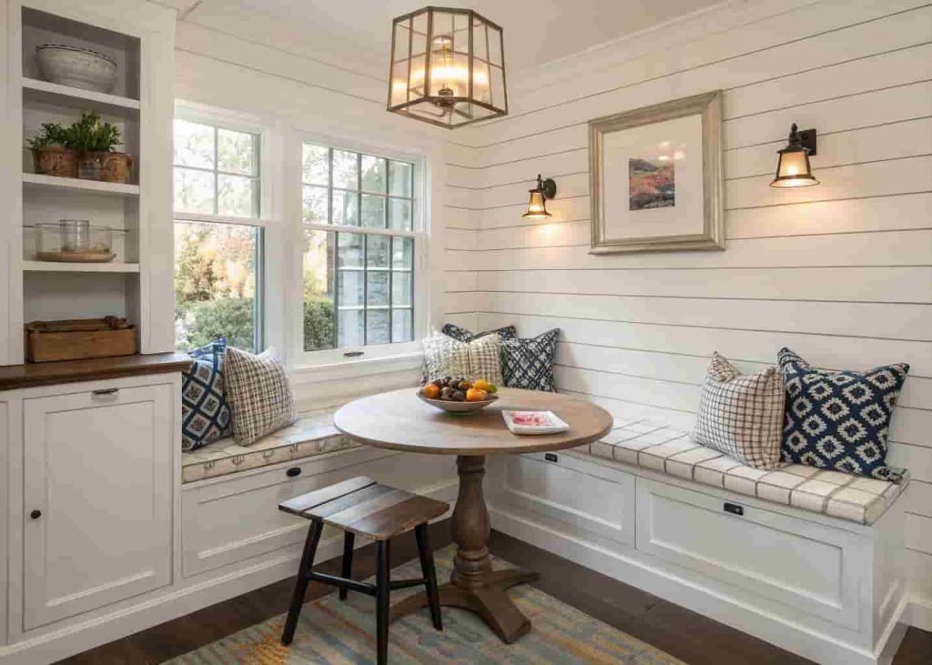 Corner bench breakfast nook with built-in storage and colorful throw pillows in a small kitchen