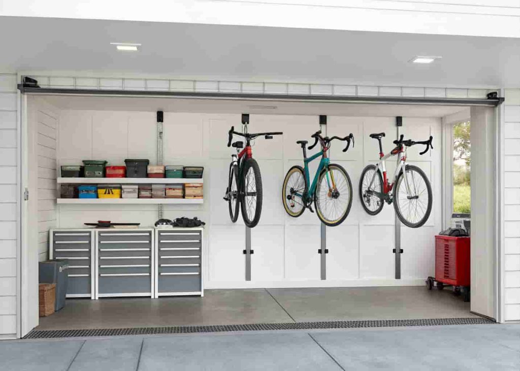 Three bicycles mounted vertically on wall hooks in a clean organized garage with painted walls