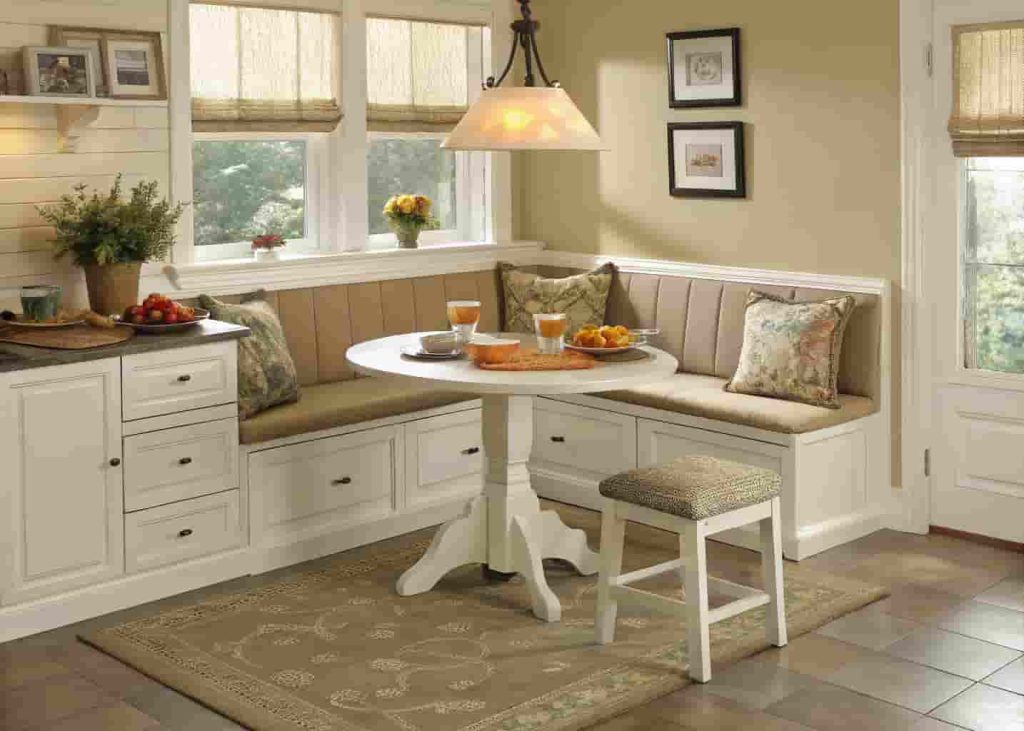 Corner banquette breakfast nook with lift-top bench storage and round table in a cozy kitchen setting