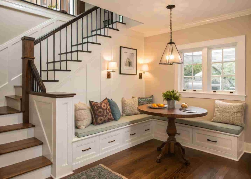 Under-stairs breakfast nook with built-in bench seating, custom storage drawers, and pendant light in a cozy home
