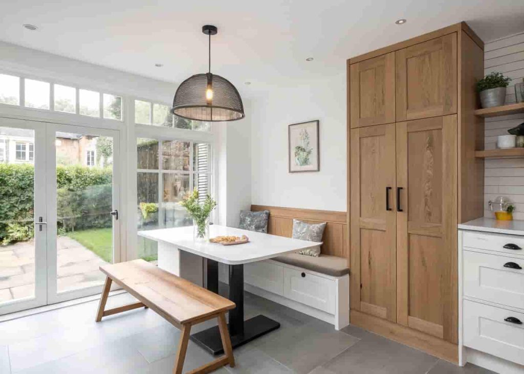 Modern breakfast nook with built-in bench seating and tall vertical cabinet storage in a clean contemporary kitchen