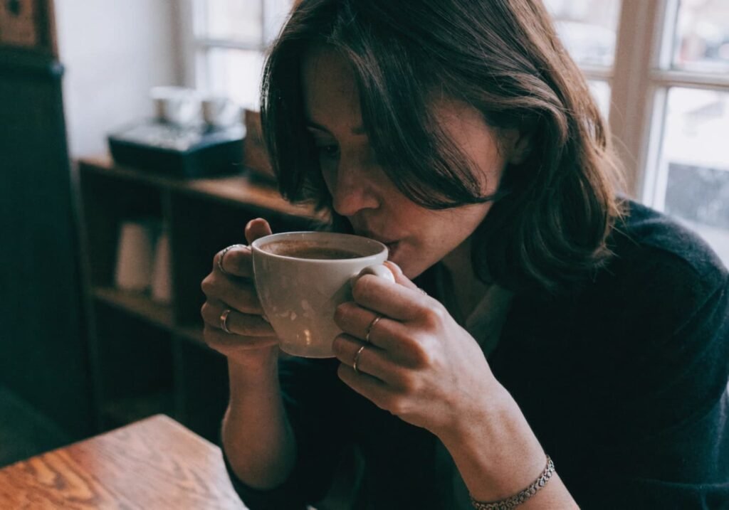 Woman holding a coffee cup naturally at a cafe table.