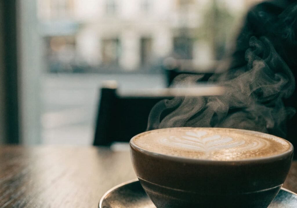 Close-up of a coffee cup with latte art and steam rising