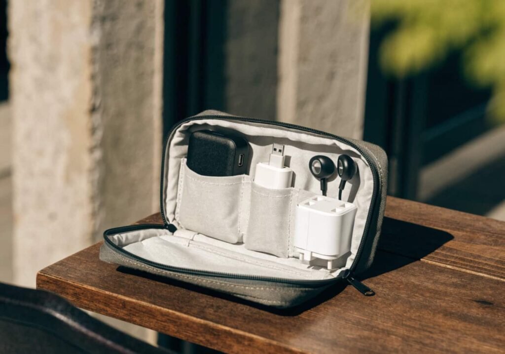Travel electronics pouch with charger, power bank, adapter, and earphones ready for packing.