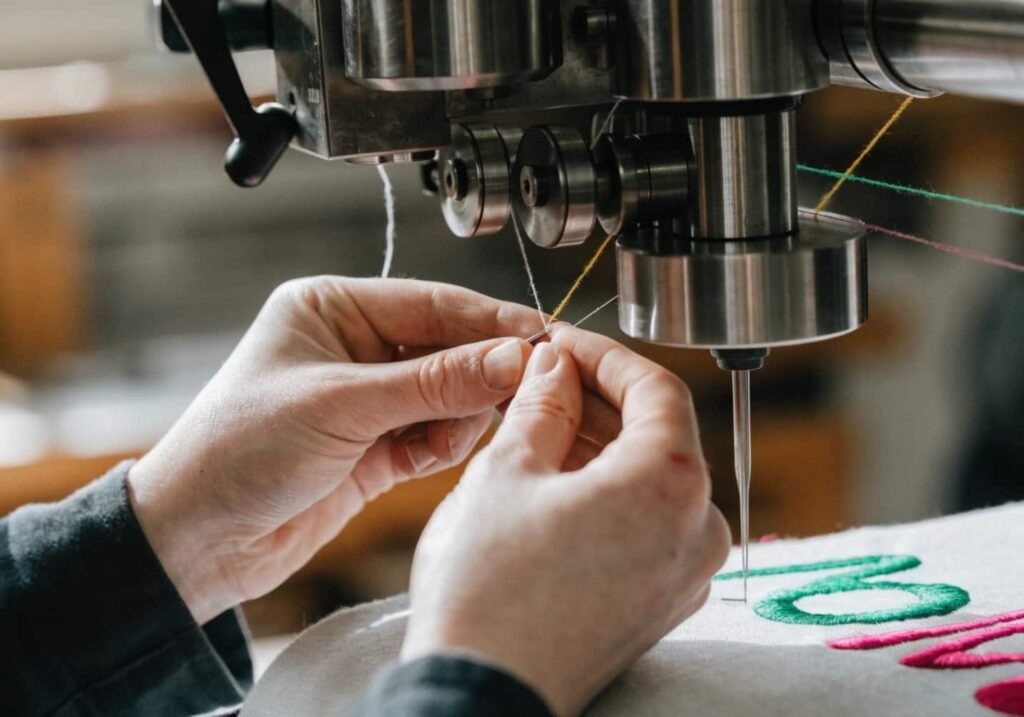 Close-up of hands adjusting thread tension while machine embroidering home decor fabric
