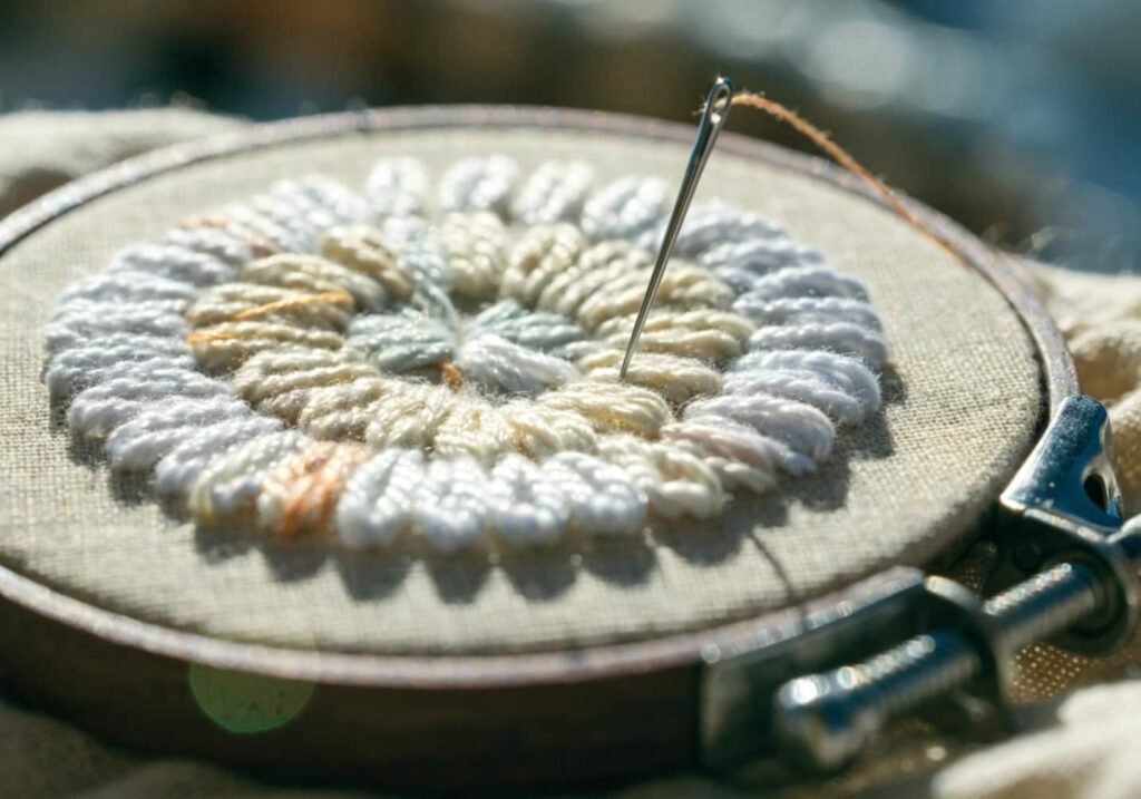 Lazy daisy stitch forming flower petals on embroidery hoop fabric
