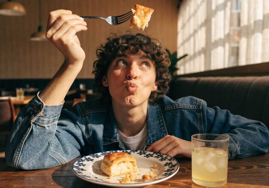Person holding a pastry with a fork at a cafe table.