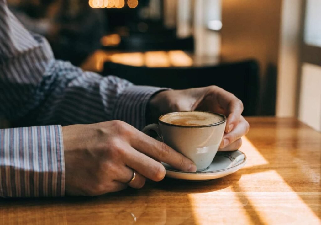 Hands holding and gently turning a coffee cup at a cafe.