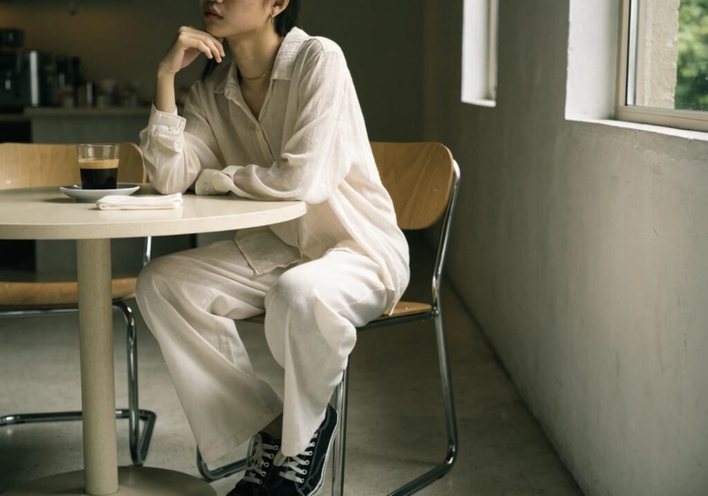 Person in a minimal aesthetic outfit sitting at a cafe table