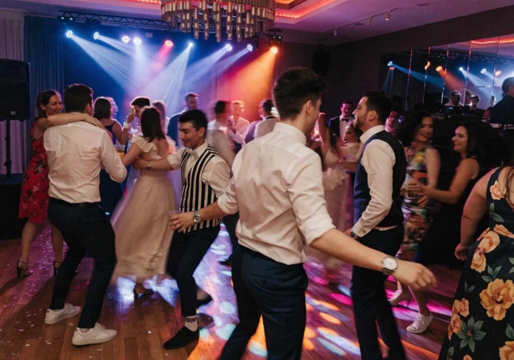 Guests dancing energetically on a packed wedding reception dance floor