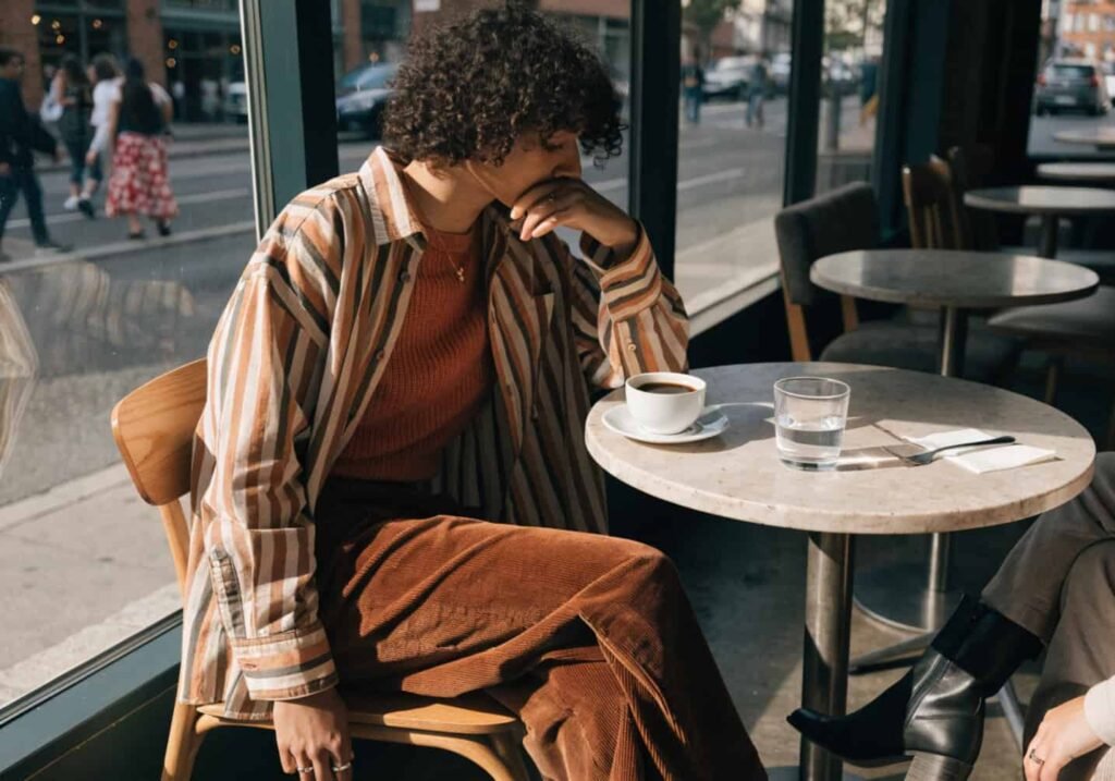Person in a seasonal outfit enjoying coffee near a cafe window