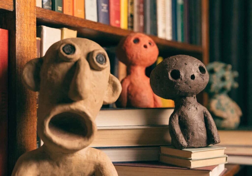 Layered bookshelf styling with clay figures at varying depths
