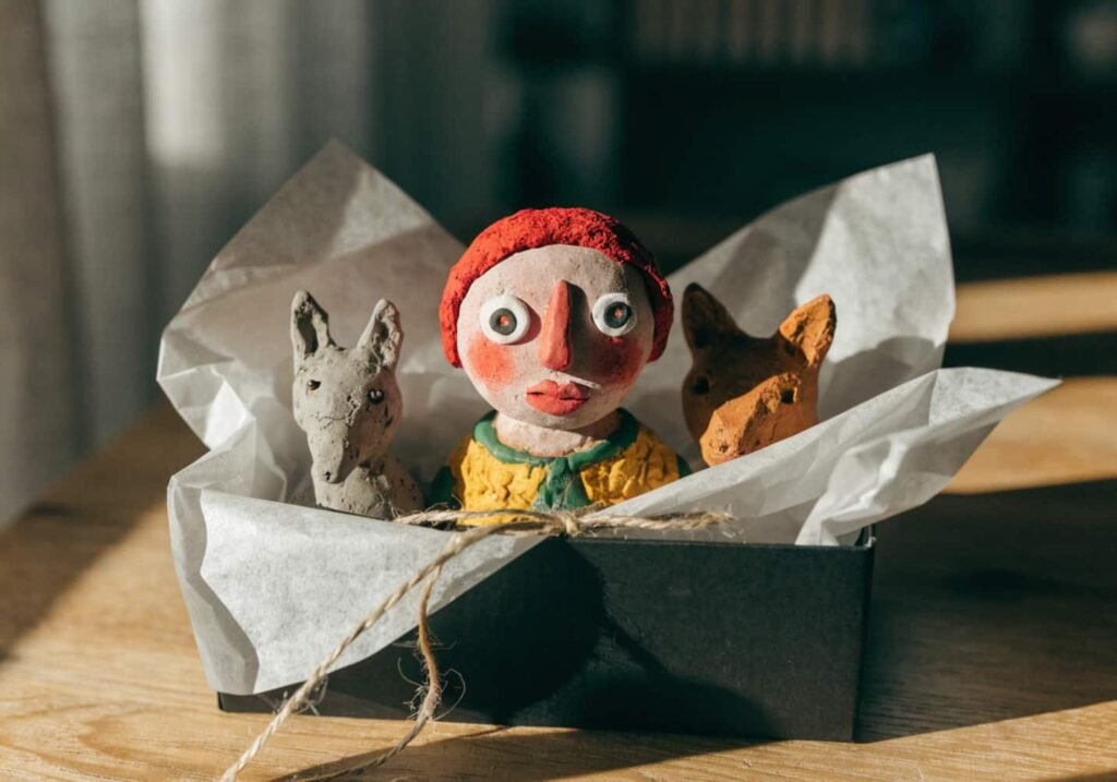 Handmade clay figures displayed in a small gift box with tissue paper