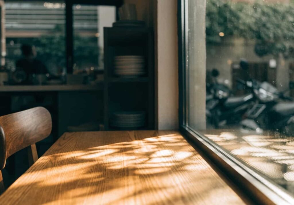 Sunlight through glass window aesthetic cafe table photo