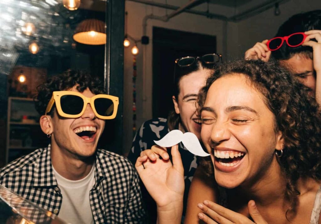 Bride and friends laughing with props inside a creative wedding photo booth