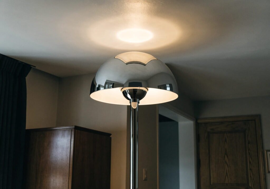 Chrome floor lamp with upward shade casting soft light in a neutral room