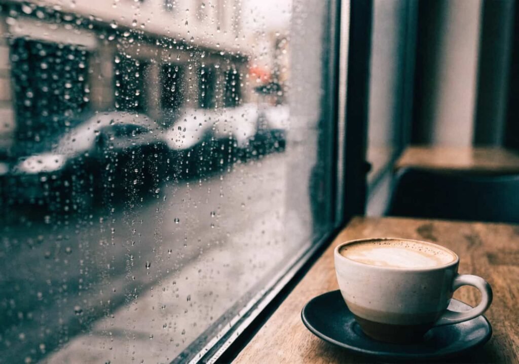 Rainy day cafe window aesthetic photo with coffee cup