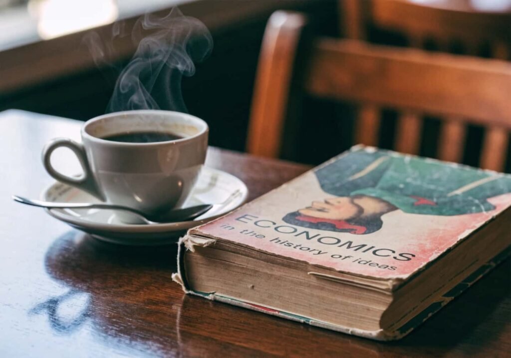 Vintage book and steaming coffee cup aesthetic setup on wooden cafe table