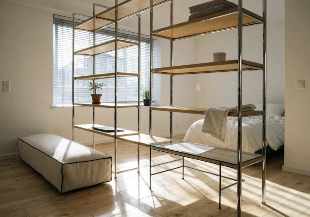 Chrome and wood shelving unit dividing a small studio apartment space