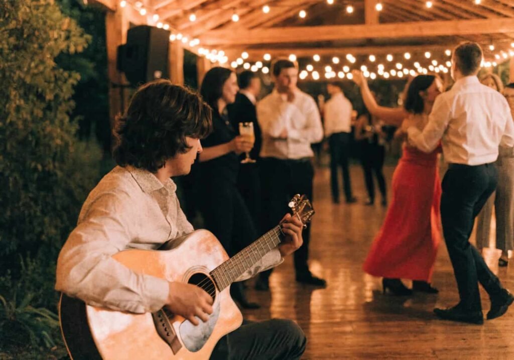 Acoustic musician performing live at a wedding reception under string lights