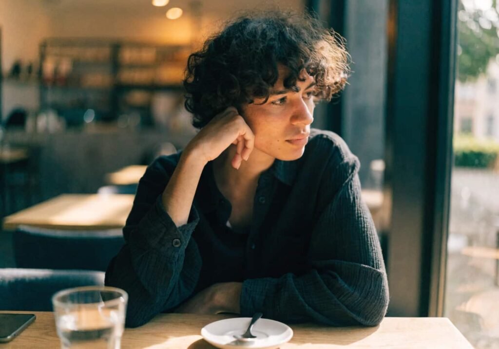 Person resting chin on hand in a relaxed cafe pose.