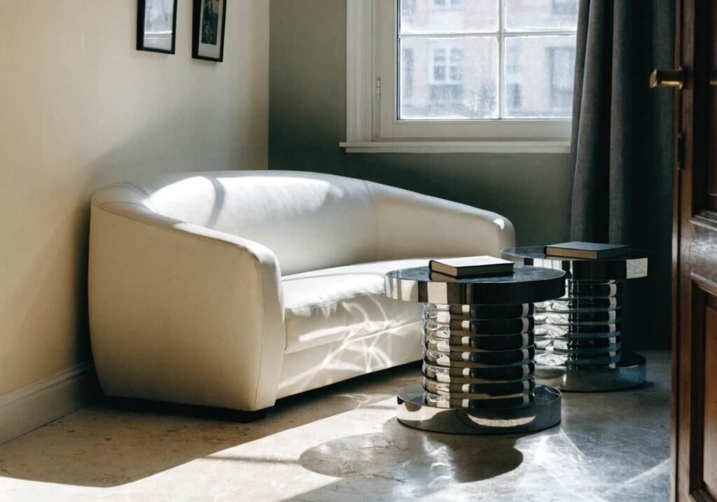 Two sleek round chrome side tables placed near a modern sofa in a bright living room