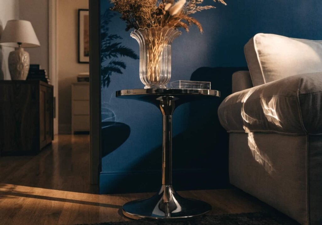 Chrome side table with glass vase and acrylic tray against a navy accent wall