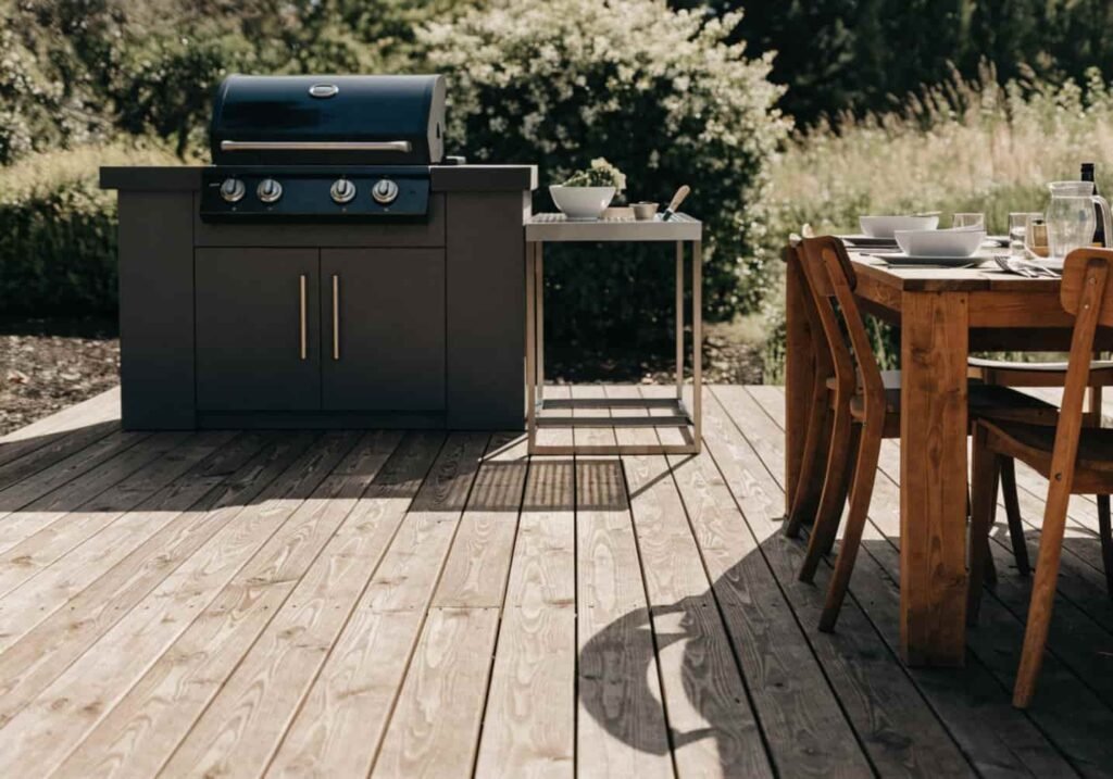 Outdoor kitchen with grill and dining table set up on a backyard deck