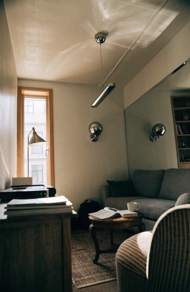 Slim chrome pendant light and wall sconces brightening a small living room