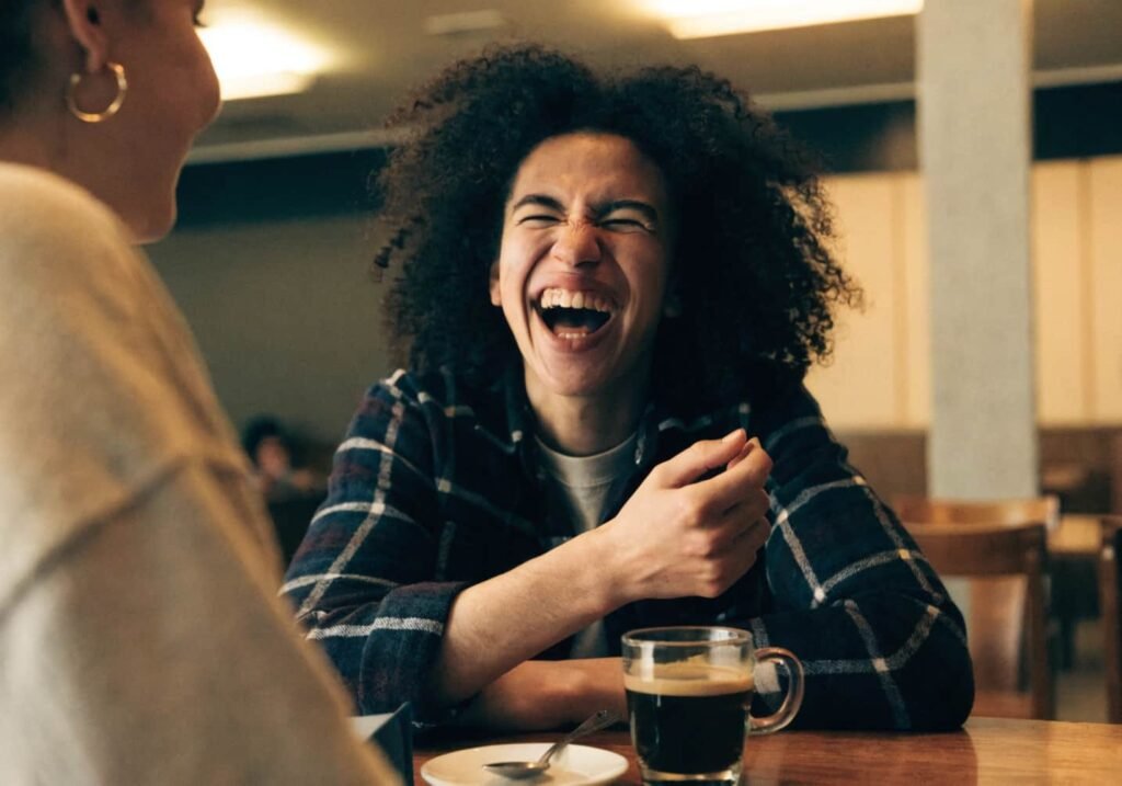 Friends laughing together over coffee at a cafe table in candid moment