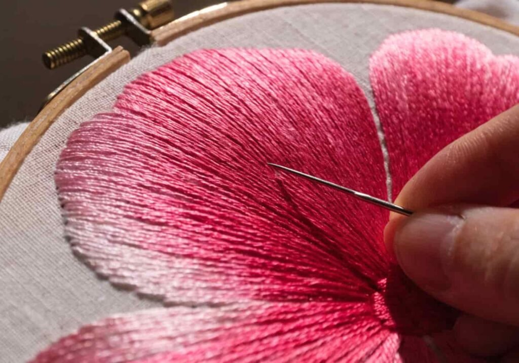 Satin stitch filling flower petal shape with smooth pink thread