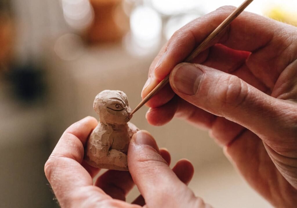 smoothing clay figure surface with damp finger
