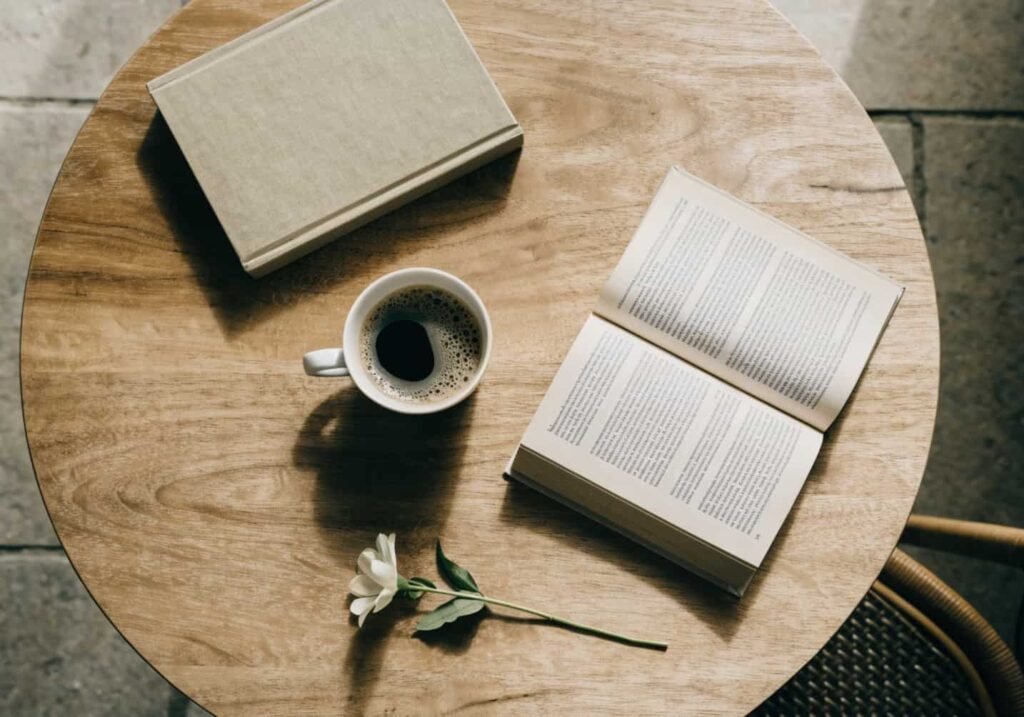 Flat lay of coffee cup, books, and flower on a cafe table