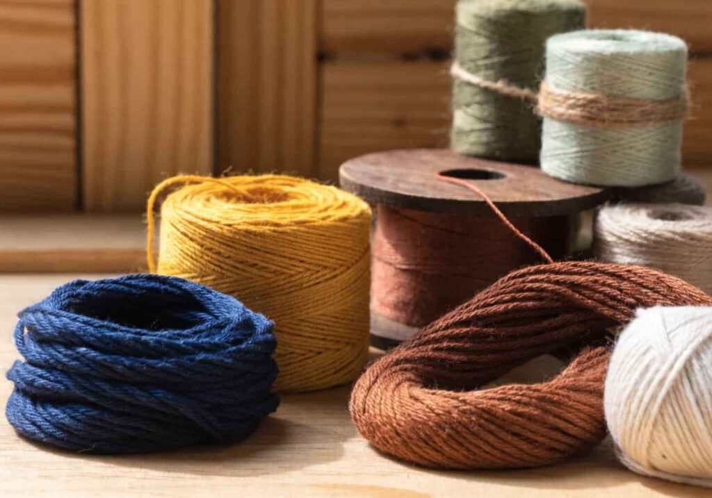 Naturally dyed eco-friendly embroidery threads in earthy tones on wood