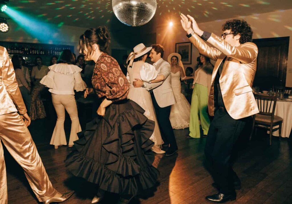 Guests dancing under a disco ball at a retro-themed wedding reception