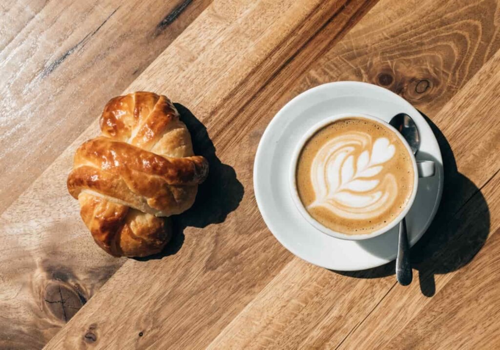 Pastry and latte art coffee cup arranged as a flat lay