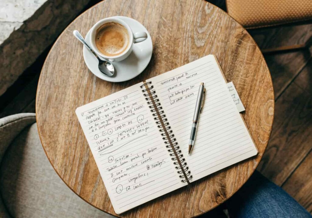 Notebook and coffee cup arranged in a cozy flat lay setup