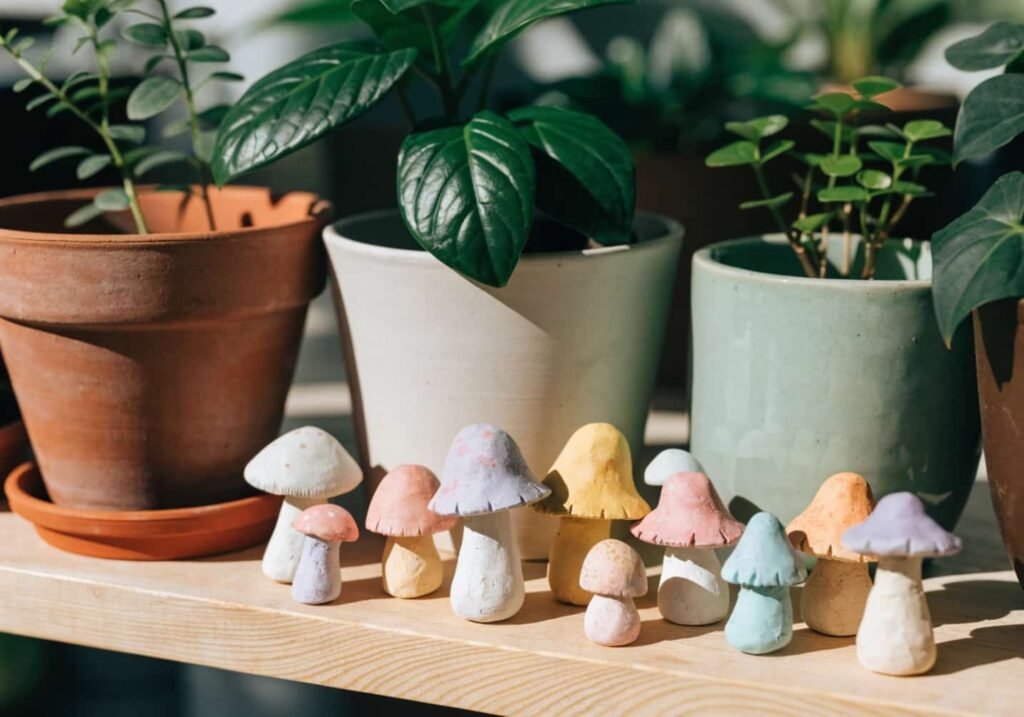 Pastel handmade clay mushroom figures placed among potted plants