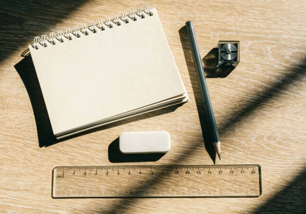 Pencil, eraser, ruler, and sketchbook laid out on a table ready for a beginner drawing session